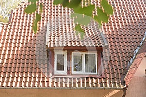 Window in old attic with tiled roof. Part of facade building from last century. Selective focus