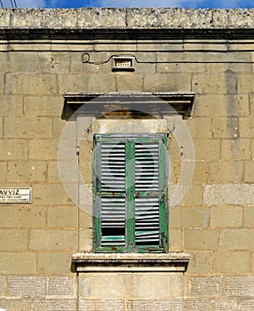 Window of the old building covered by green wooden blinds in Rabat town on Malta