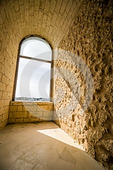 Window in old fortress with sunny harbor behind