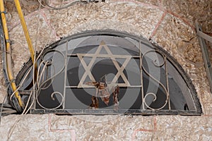 A window in an old, Jerusalem apartment building with a metal grate and Jewish star of David