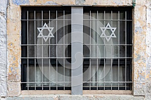 A window in an old, Jerusalem apartment building with a metal grate and two Jewish stars of David