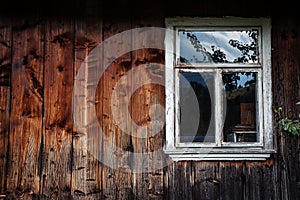 The window of the old wooden log house on the background of wood