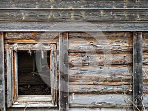 The window of the old wooden log house on the background of wooden walls