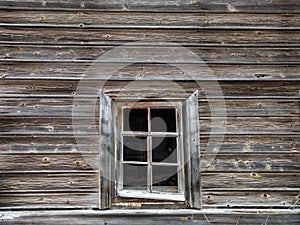 The window of the old wooden log house on the background of wooden walls