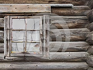 The window of the old wooden log house on the background of wooden walls