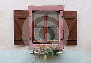 Window with open brown wooden shutters and a metal flower pot