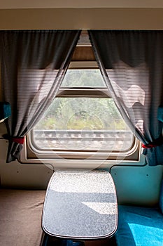 A window and part of the interior of a compartment car inside a traveling train in summer