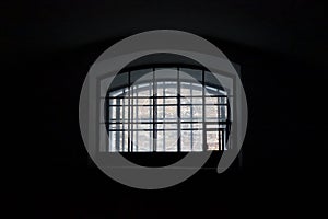 A window in a prison cell, covered with bars.