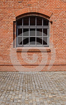 The window in red brick wall with cobblestones.