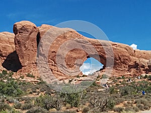 Window Rock at Arches National Park, with hikers walking toward it