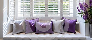 Window seat with purple pillows, white shutters, and chic interior design