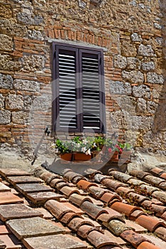 Window with shutter in Tuscany with flowers and brick