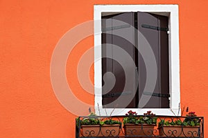 Window shutters closed on orange wall