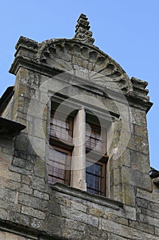 The window of a stone house situated in Rocherfort-en-terre, France, is surmounted by a sculptured curved pediment