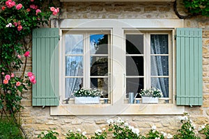 Window in a stone wall with green shutters