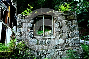 A window in the stone wall of the ruins of a mountain house damaged by an earthquake and a landslide in the mountains. a hut destr