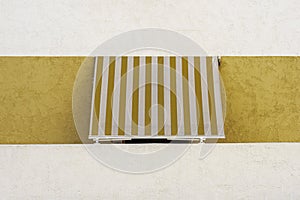 Window with striped shade sail sun protection in white and yellow wall. Minimal background