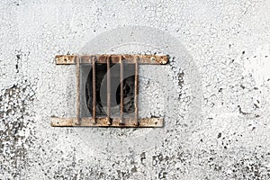 Window or sunroof in the wall with metal grille. Old wall with cracked paint and rusty grille on the window