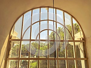 Window to the floor in a hotel for tourists. glass window with a metal grill on top. greenery, trees outside