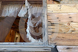 Window with a torn screen at Bonnie Claire Ghost Town in Nevada, USA