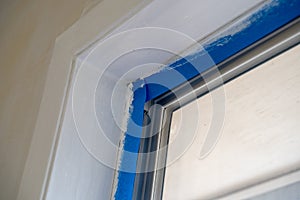 Window trim covered with blue painters tape during home renovation improvements during painting photo