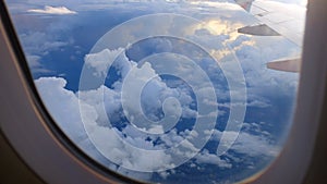 Window View on Airplane, Wing of Airplane With Sunlight on Sky, Cloudy Background,