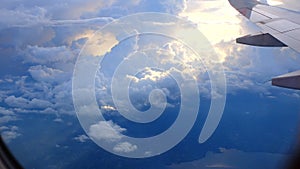 Window View on Airplane, Wing of Airplane With Sunlight on Sky, Cloudy Background,