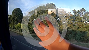 Window view of moving bus and girl`s hand rests on the glass.