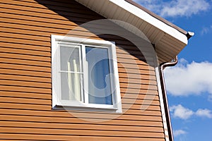 Window in wall of brown vinyl siding