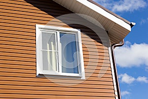 Window in wall of brown vinyl siding