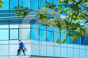 Window washer cleaning facade of modern office building