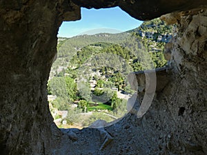 Window on the wooded and verdant hills of Fontaine de Vaucluse in Provence with the Sorgue river below