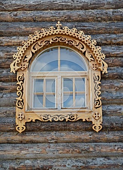 Window with wooden carved platbands on a timbered wall