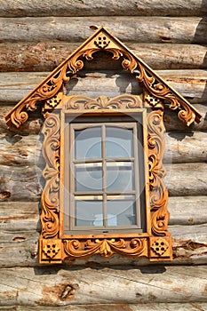 Window with wooden carved platbands on a timbered wall