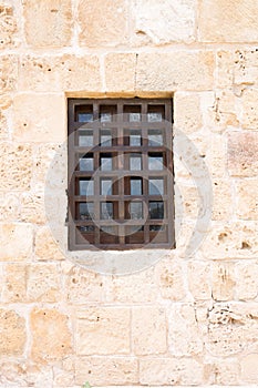 window with wooden grill on ancient wall