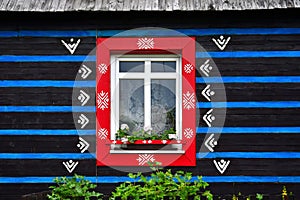 A window of a wooden house with blue, red and white colors in the small town Zdiar near the High Tatras, Slovakia