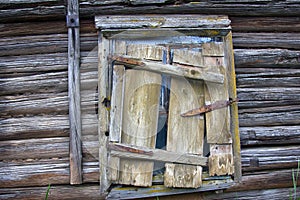 Window of wooden house closed with collapsed shutter