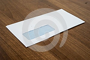 Windowed envelope lying on brown wood table