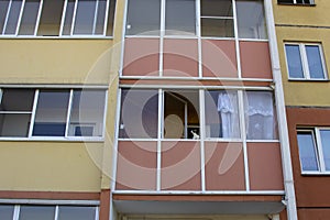 Windows and balconies of a block of flats. The cat is sitting on the balcony. The photo