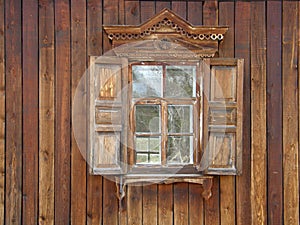 The windows with beautiful architraves in old wooden house.