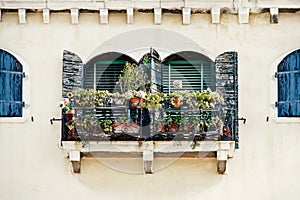 Windows with blue shutters and flowers on the yellow facade in old house in Venice