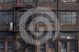 Windows, doors, and fire escape on the exterior of a derelict industrial building