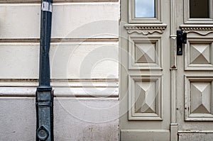 Windows in the old door and a house wall or facade with downpipe of the gutter