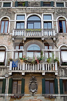 windows in an old house decorated with flowers and flags, Venice, Italy