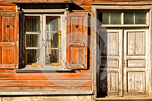Windows with open shutters and closed doors of an old wooden building