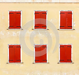 Windows with red wooden shutters on a weathered wall, closeup background.