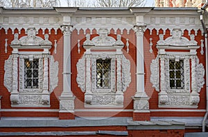 Windows with stucco platbands and bas-reliefs against the background of the red brickwork