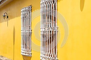Windows with white iron decoration on yellow wall