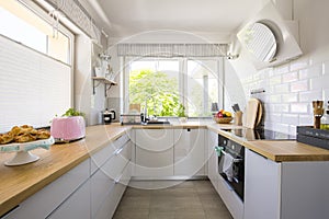 Windows in white kitchen interior with grey cabinets and wooden