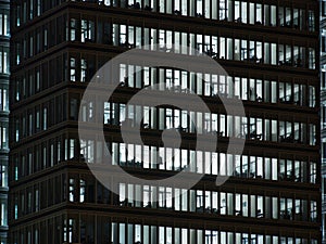 Windows of white lit offices in tall Office building